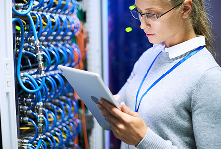 woman looking at tablet in front of a network rack