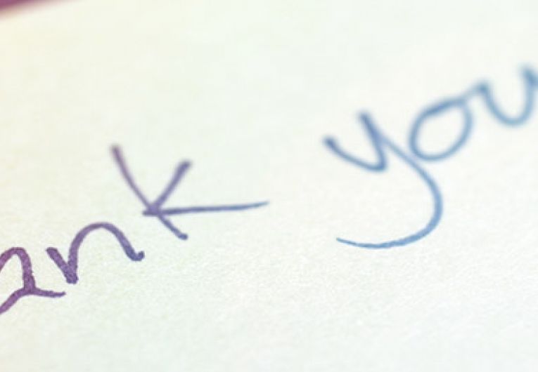 close up of someone writing thank you on a piece of paper